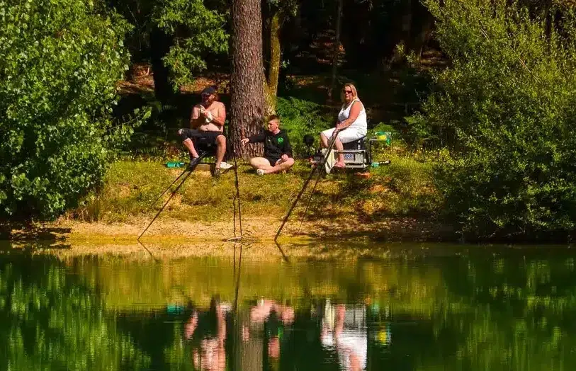 Couple avec un enfant installé devant ses cannes au bord de l’étang
